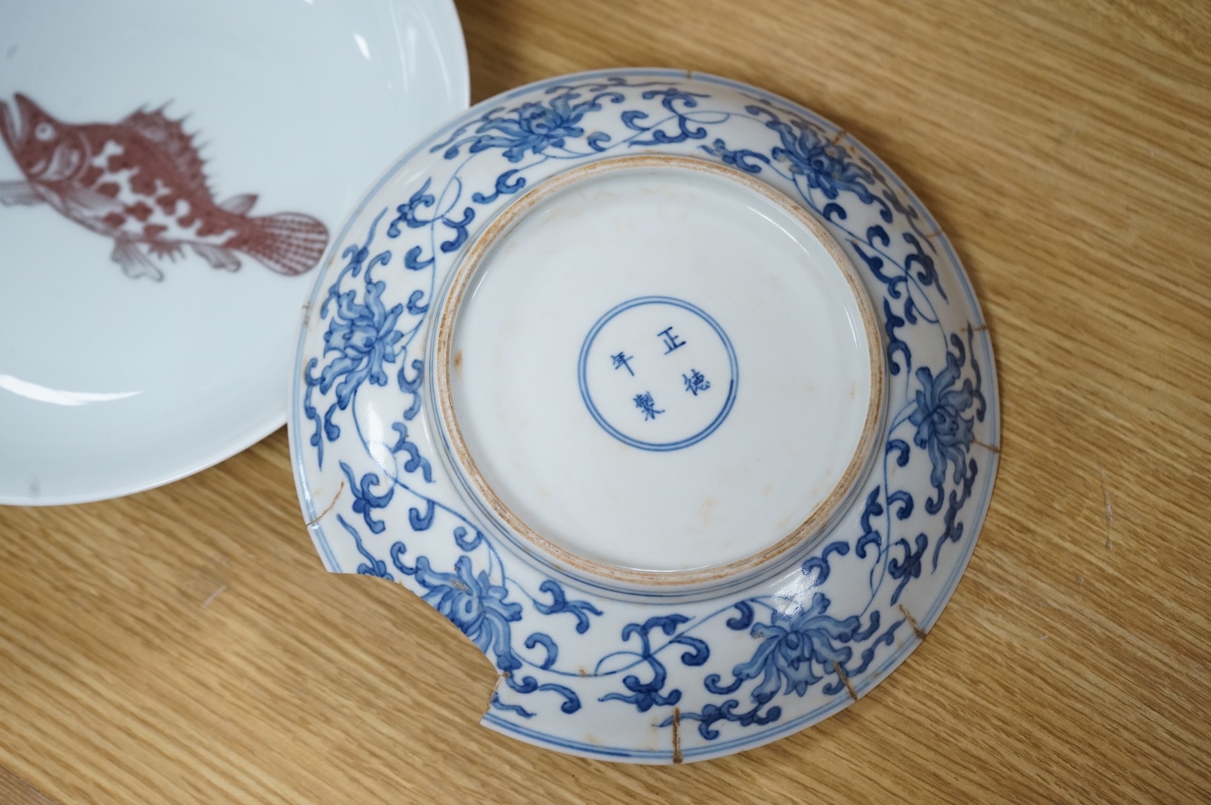 A Chinese underglaze copper red ‘fish’ dish and a blue and white dish, Zhengde mark but later, largest 22cm
